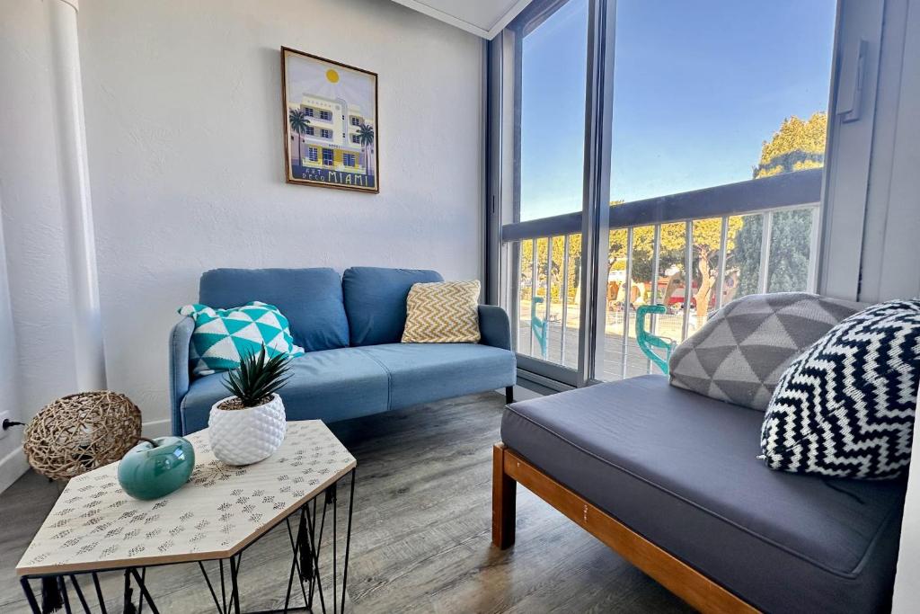 un salon avec un canapé bleu et une table dans l'établissement LE CABESTAN - studio proche plage, au Grau-du-Roi