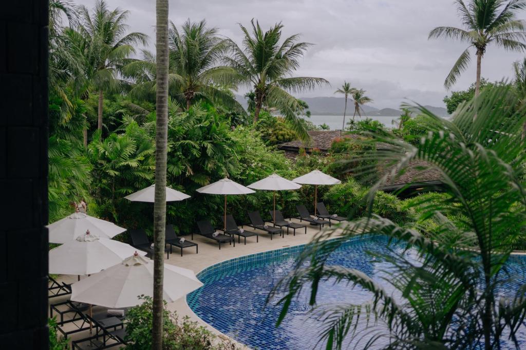a resort pool with chairs and umbrellas at Barcelo Coconut Island, Phuket in Phuket Town
