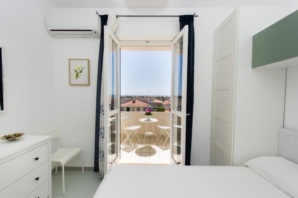 マリーナ・ディ・モーディカにあるvilletta rosa blu marina di modicaのベッドルーム1室(ベッド1台付)、バルコニー(テーブル付)
