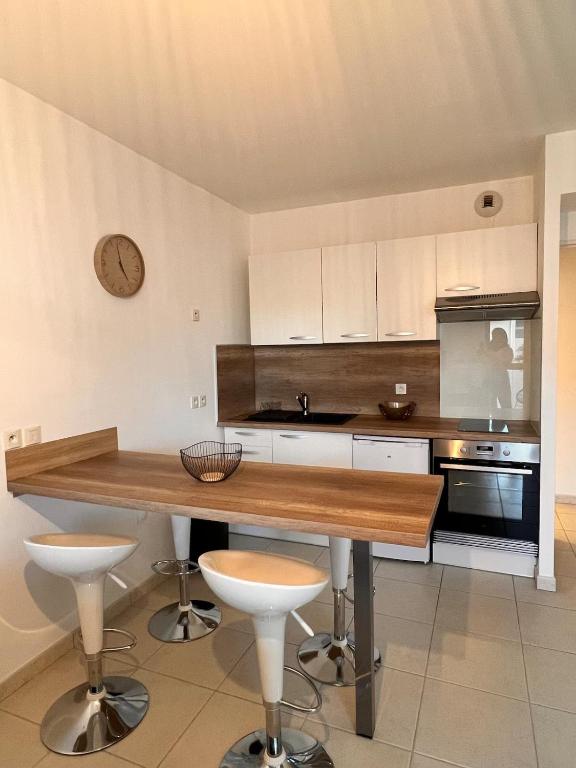 une cuisine avec une table en bois et une horloge au mur dans l'établissement Côté Port, à La Ciotat