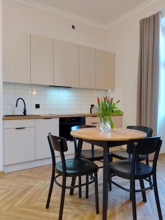 a kitchen with a wooden table and black chairs at Apartament przy Ratuszu in Płock