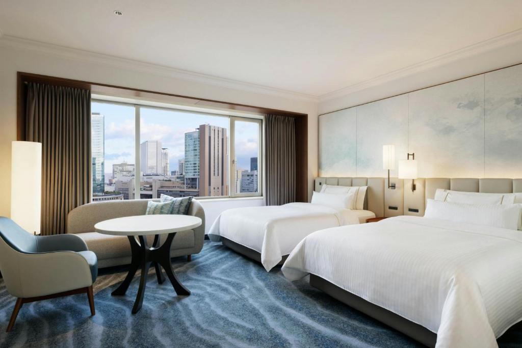 a hotel room with two beds and a table at The Westin Osaka in Osaka