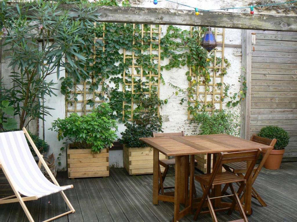 une table et des chaises sur une terrasse avec des plantes dans l'établissement Mais 5 pièces Oléron 8 couchages Saint Georges d'Oléron SGO000-905, à Saint-Georges-dʼOléron