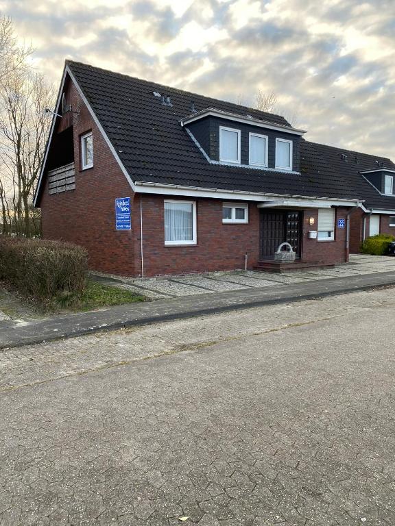 a red brick house with a black roof on a street at Apartments Bensersiel in Esens