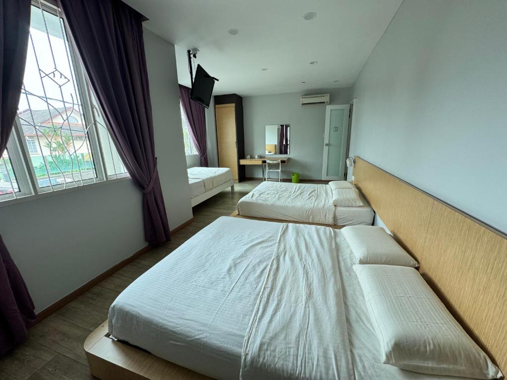two beds in a room with two windows at Tropical villa in Kuantan