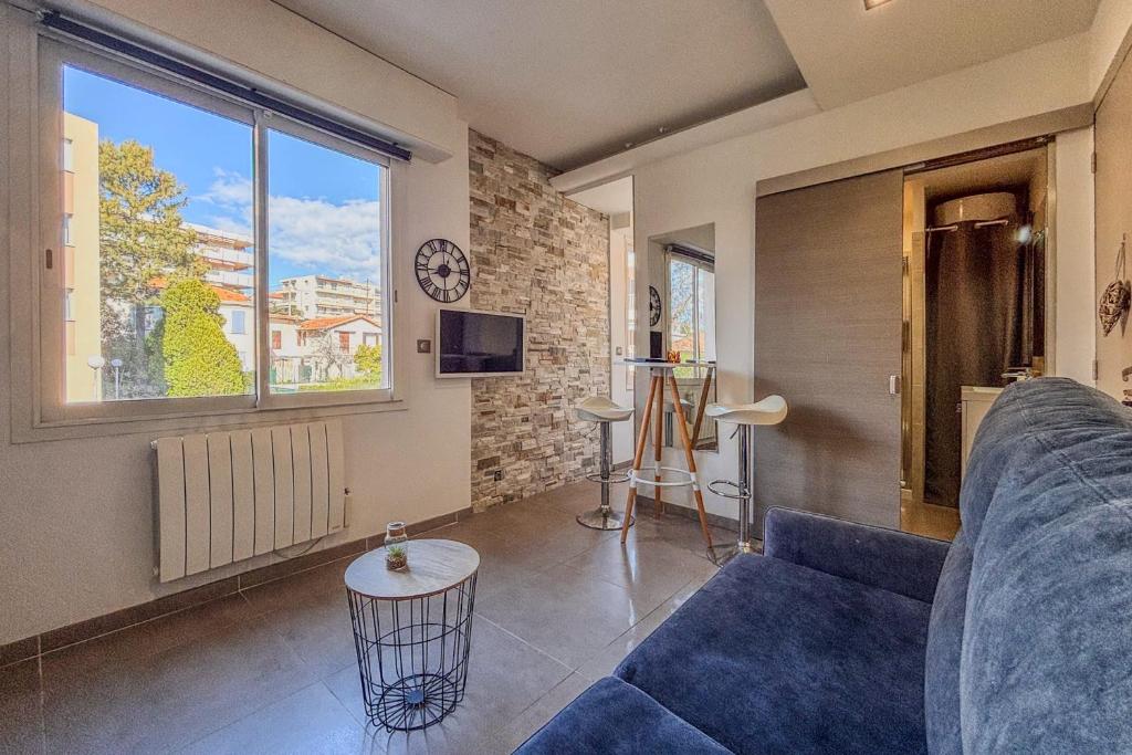 un salon avec un canapé bleu et une fenêtre dans l'établissement Contemporary 2P Studio Just Steps from the Beach, à Cagnes-sur-Mer