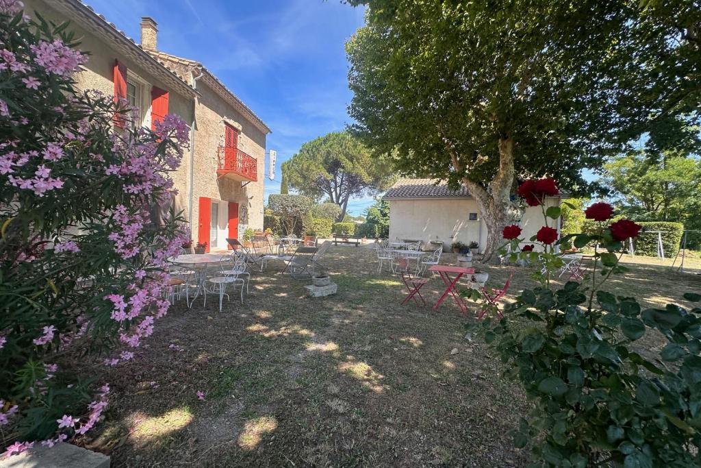 un jardin avec des tables et des chaises et un bâtiment dans l'établissement Gîte du Mas - Charmant Gîte provençal avec jardin commun, à Aigues-Mortes