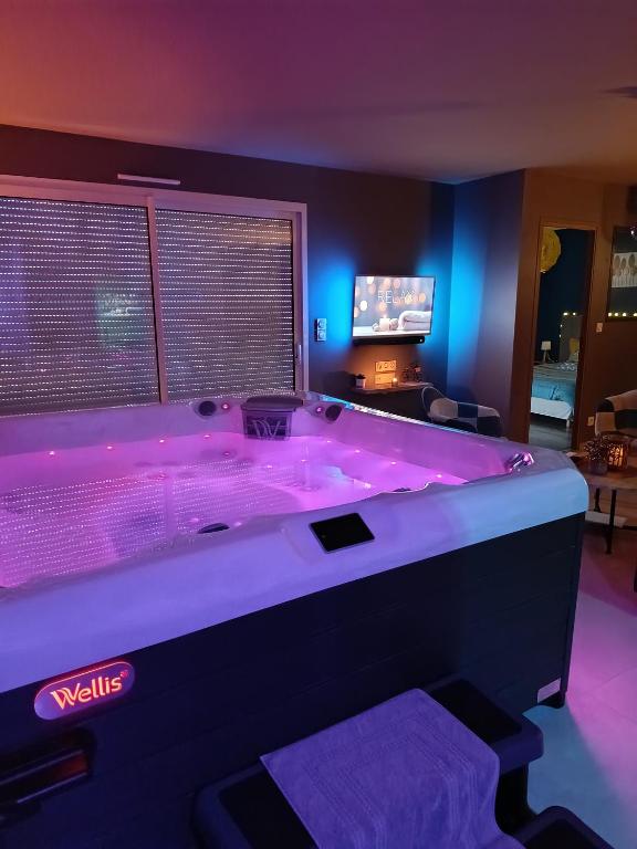 Cette chambre dispose d'une grande baignoire avec des lumières violettes. dans l'établissement Le NaturOspa spa privatif, à Le Quesnoy-en-Artois