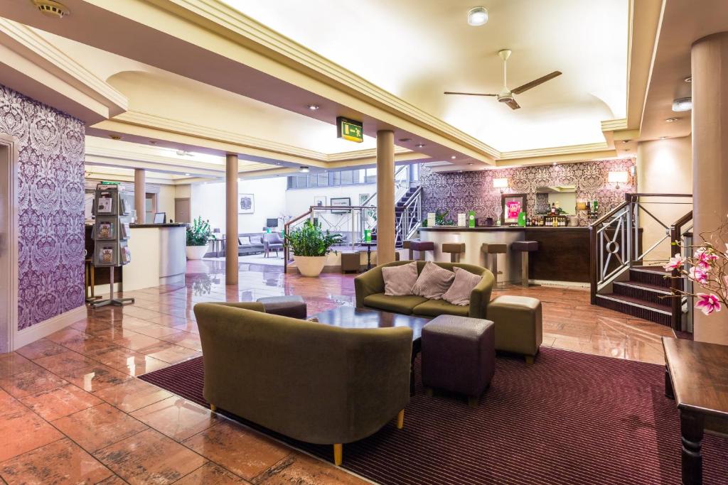 un vestíbulo de un hotel con sillas y mesa en The Gardens Hotel en Mánchester