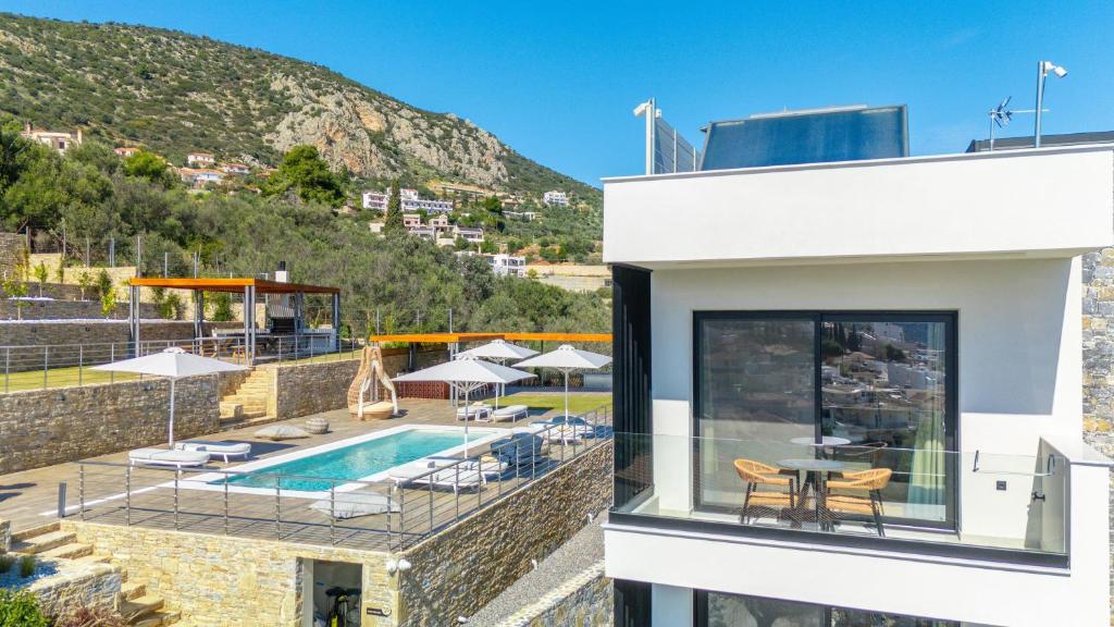 a house with a swimming pool and a patio at Yiannis Place in Tolo