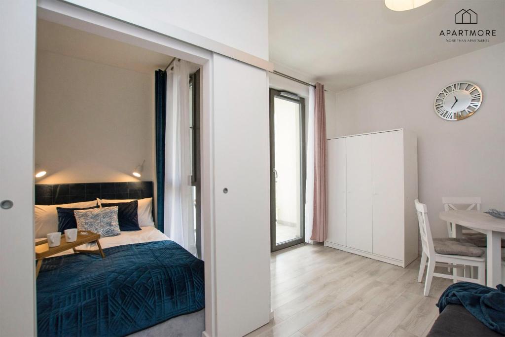 Studio interior with bed in alcove, sliding doors open to dining area, wardrobe and balcony door.