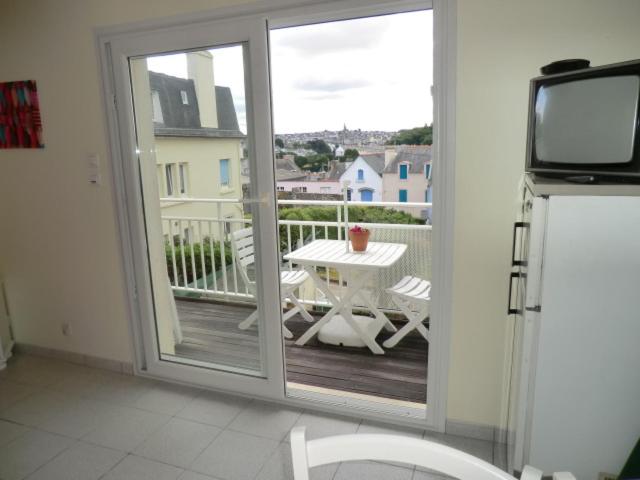 Cette chambre dispose d'une porte coulissante en verre avec une table sur le balcon. dans l'établissement DOUARNENEZ Tréboul près des plages, à Douarnenez
