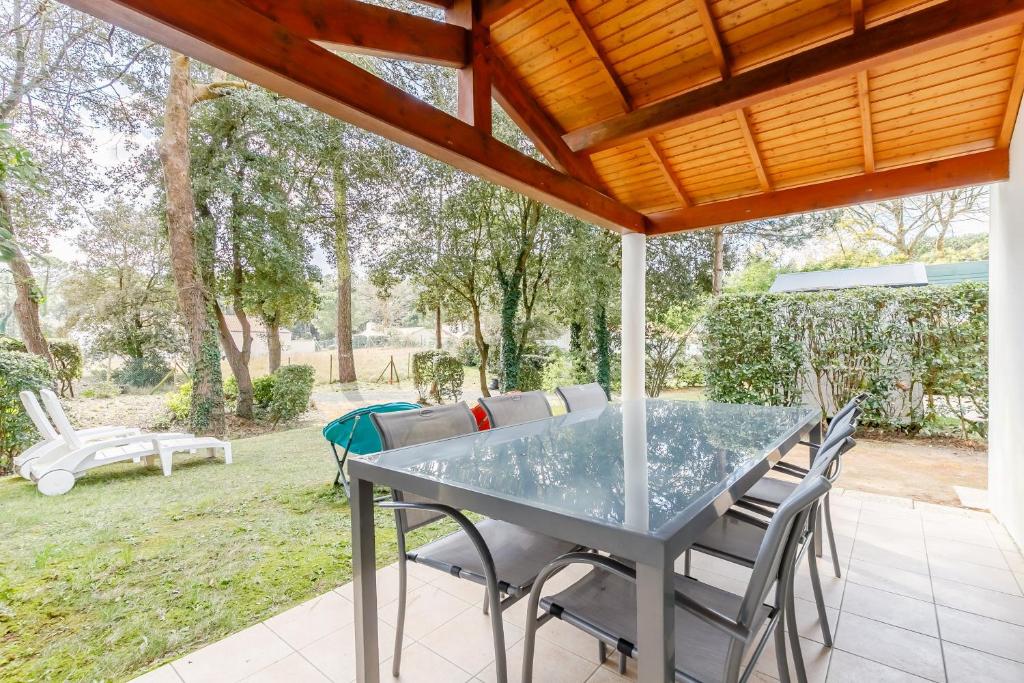 une table et des chaises en verre sur la terrasse dans l'établissement Le 113 Dunes - Jardin parking proche plage, à Saint-Jean-de-Monts