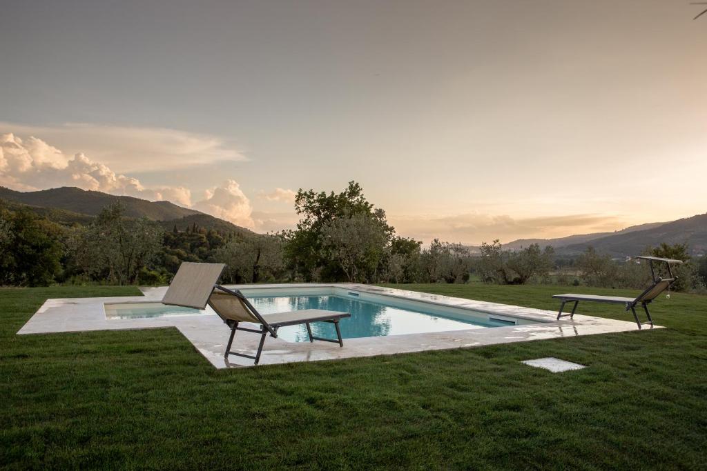 a swimming pool with two chairs and a table at Villa Gaggioleto in Castiglion Fiorentino