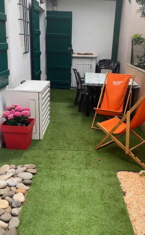 d'une terrasse avec de la pelouse verte, une table et des chaises. dans l'établissement Hossegor Centre Ville T2 Rez de Chaussée Terrasse, à Hossegor