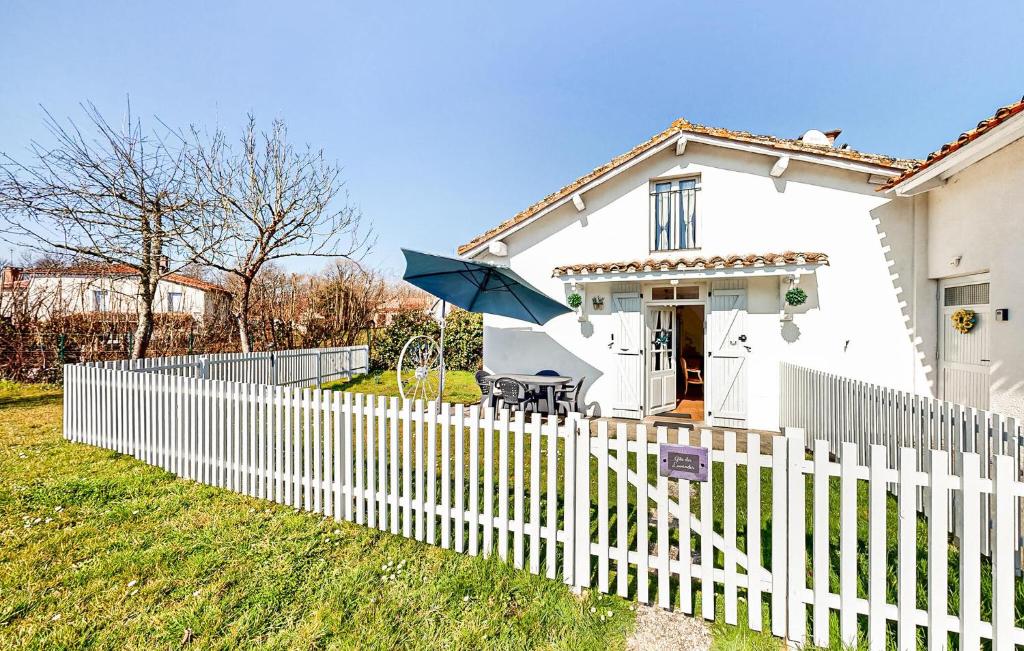 a white house with a fence and an umbrella at Lovely Home In Oradour-Fanais With Wifi in Oradour-Fanais