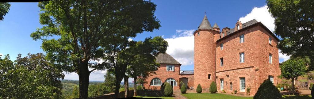 un gran edificio de ladrillo rojo con una torre en Château de Marsac, en Meyssac