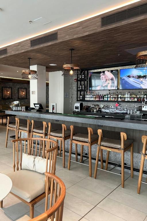 a restaurant with a bar with chairs and a tv at Fairfield by Marriott San Jose Airport Alajuela in Alajuela City