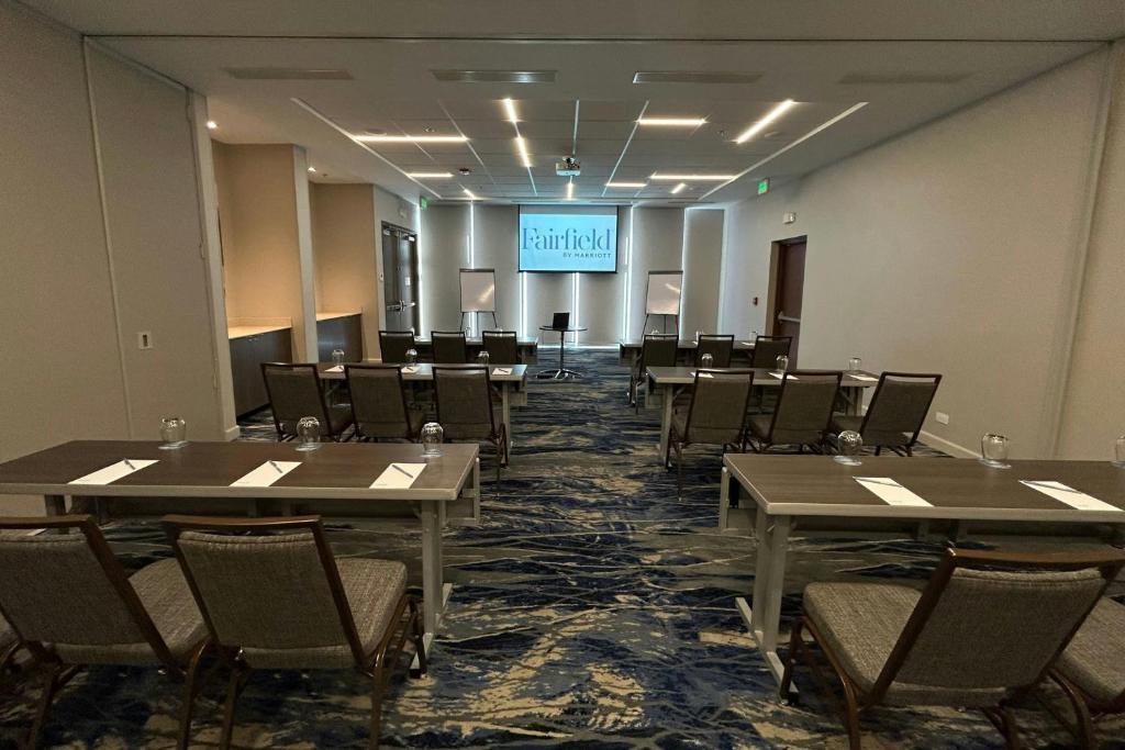 a conference room with tables and chairs and a screen at Fairfield by Marriott San Jose Airport Alajuela in Alajuela City