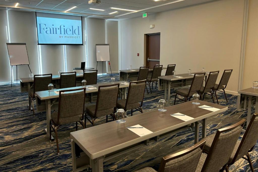 a conference room with tables and chairs and a screen at Fairfield by Marriott San Jose Airport Alajuela in Alajuela City