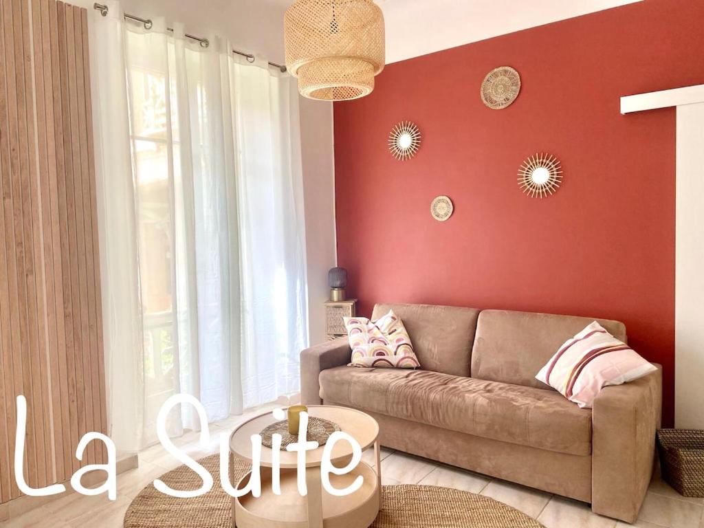 - un salon avec un canapé et un mur rouge dans l'établissement La Suite, à Beausoleil