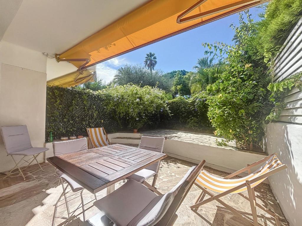un patio avec une table et des chaises en bois dans l'établissement A deux pas des plages piscine 346L FRANCHI, à Cannes