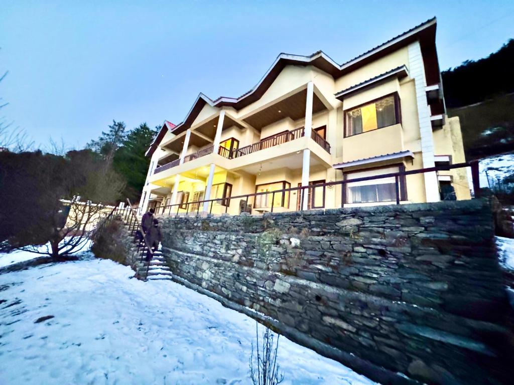 a man standing in front of a house in the snow at Kufri Home I Charvi Retreat By Exotic Stays in Kūfrī