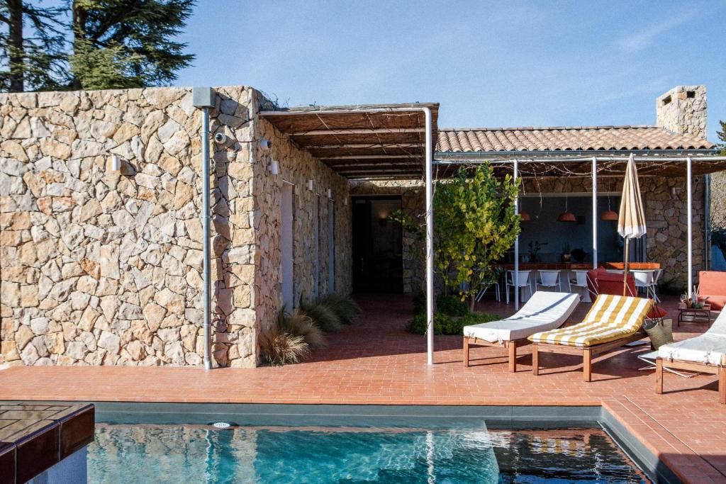 a house with a swimming pool next to a stone wall at Villa St Remy Centre Piscine chauffée et Hammam in Saint-Rémy-de-Provence