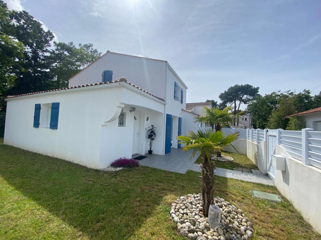 une maison blanche avec un palmier dans la cour dans l'établissement Jolie maison de vacances avec wifi, à La Tranche-sur-Mer