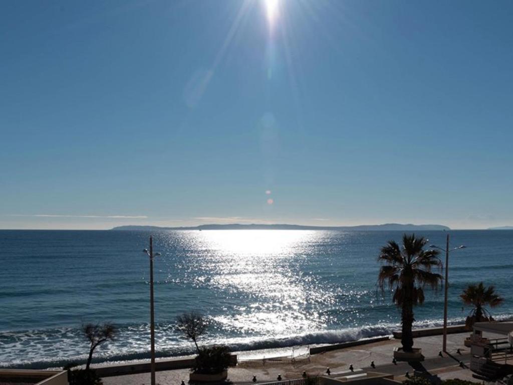 - une vue sur l'océan et le soleil réfléchissant sur l'eau dans l'établissement Studio 4 personnes, face plage, parking, climatisation - Le Lavandou - FR-1-803-22, au Lavandou