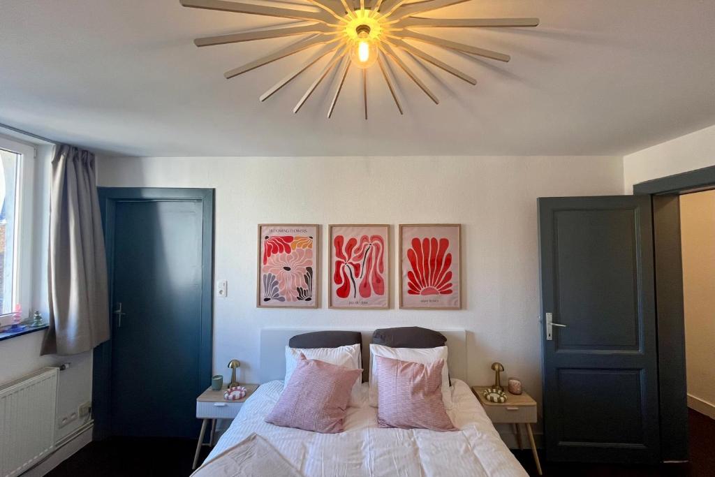 a bedroom with a bed with a large chandelier at Rutxhiel - Appartement 3e étage in Liège