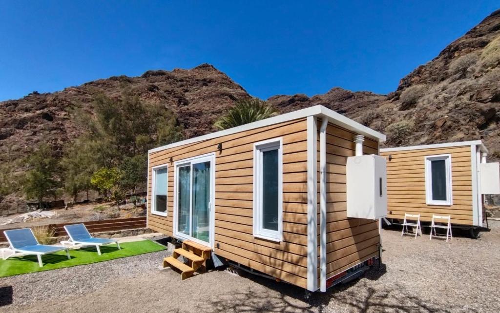 una casa pequeña con una montaña en el fondo en Blue Ocean Camp - Tasartico, en Tasartico