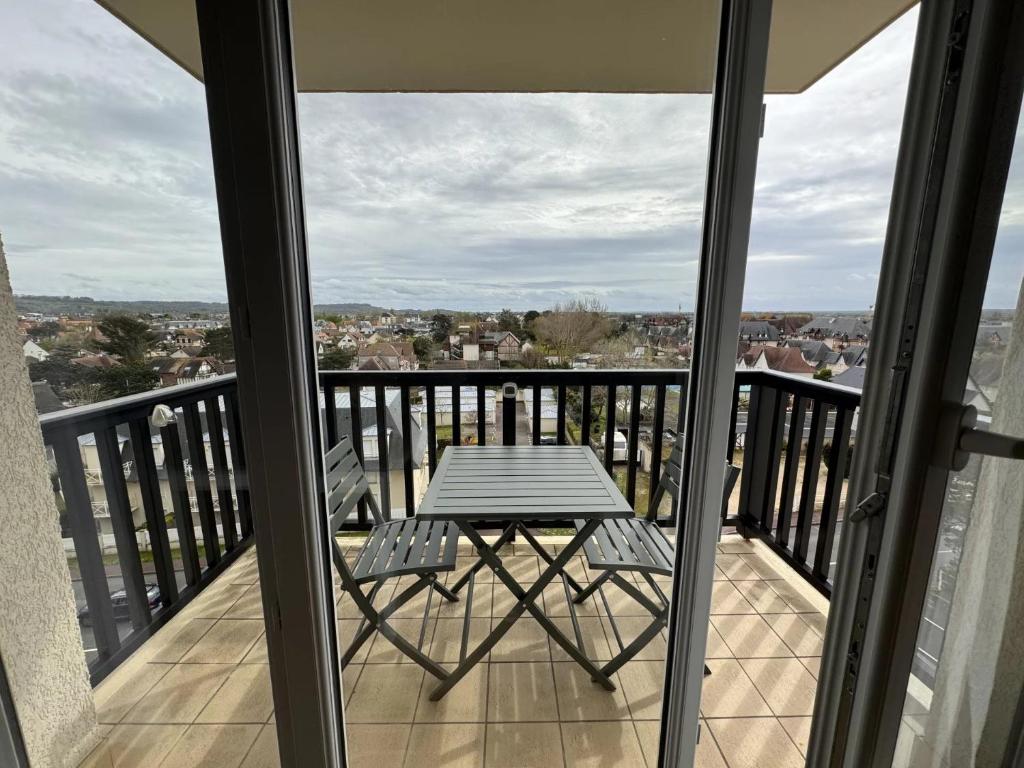 - une table sur un balcon avec vue sur la ville dans l'établissement Proche Mer - 2 pièces Balcon au SUD, à Cabourg