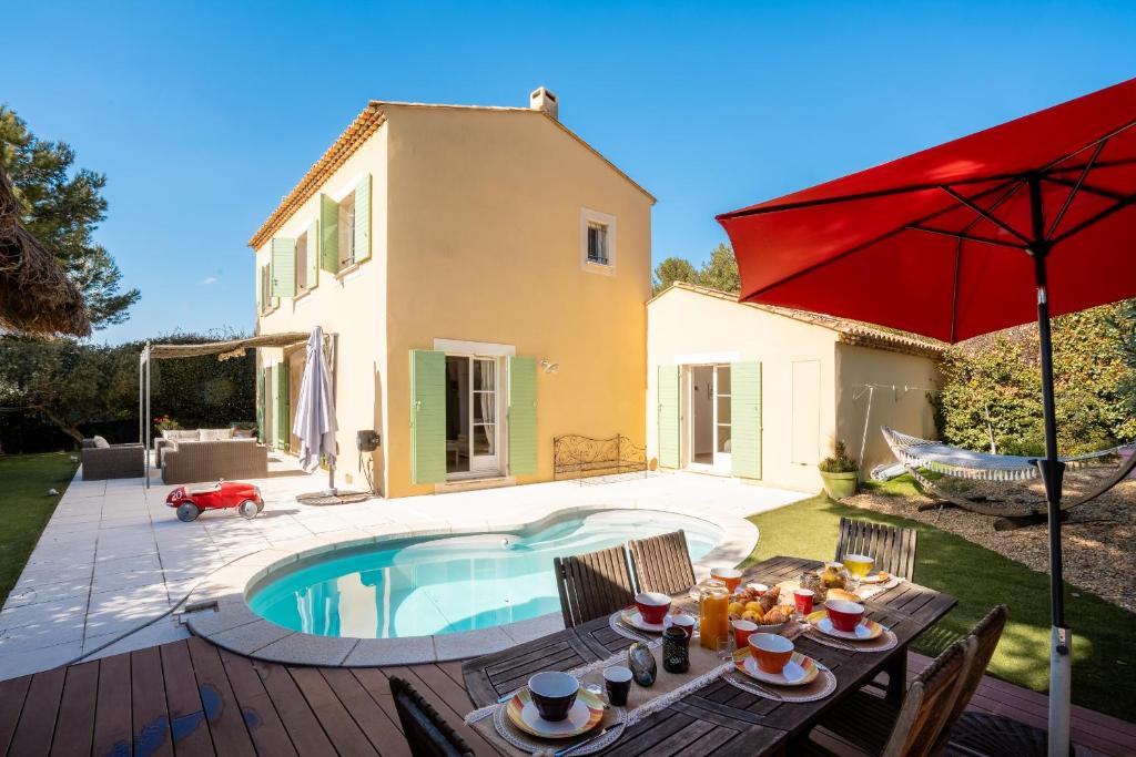une terrasse avec une table, un parasol et une piscine dans l'établissement Villa avec Piscine sur le Golf, à Béziers