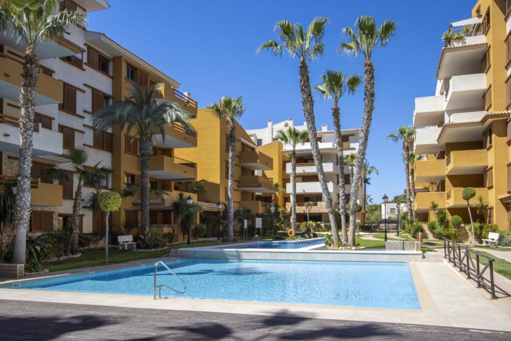 a swimming pool in front of a building with palm trees at La Recoleta ID198 in Cabo Roig