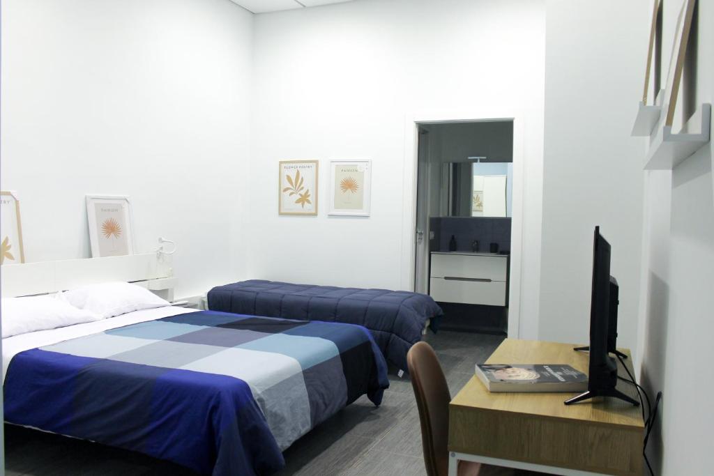 a bedroom with two beds and a desk and a television at di fronte al museo in Gela