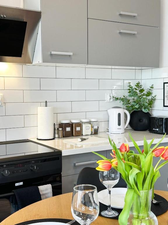a kitchen with a table with a vase of flowers at Apartamenty Prestige Harmony Arnikowa in Augustów