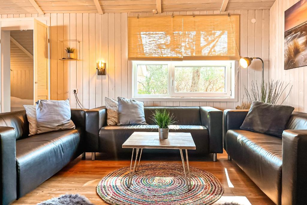 a living room with leather couches and a table at Strandblick - Dorf 1 Ferienhaus 16 in Priwall