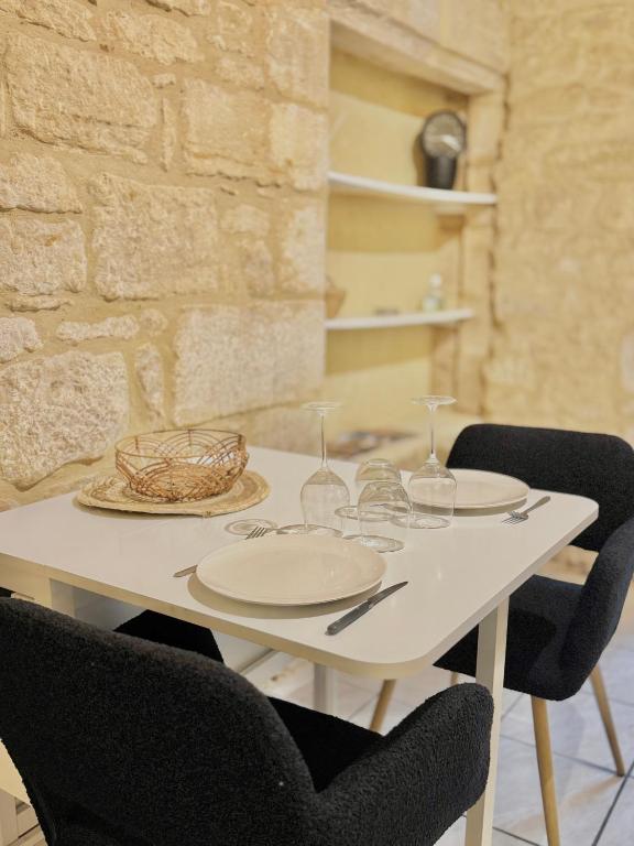 - une table blanche avec des assiettes et des verres à vin dans l'établissement La Casa de Pipo Au cœur de Sarlat, à Sarlat-la-Canéda