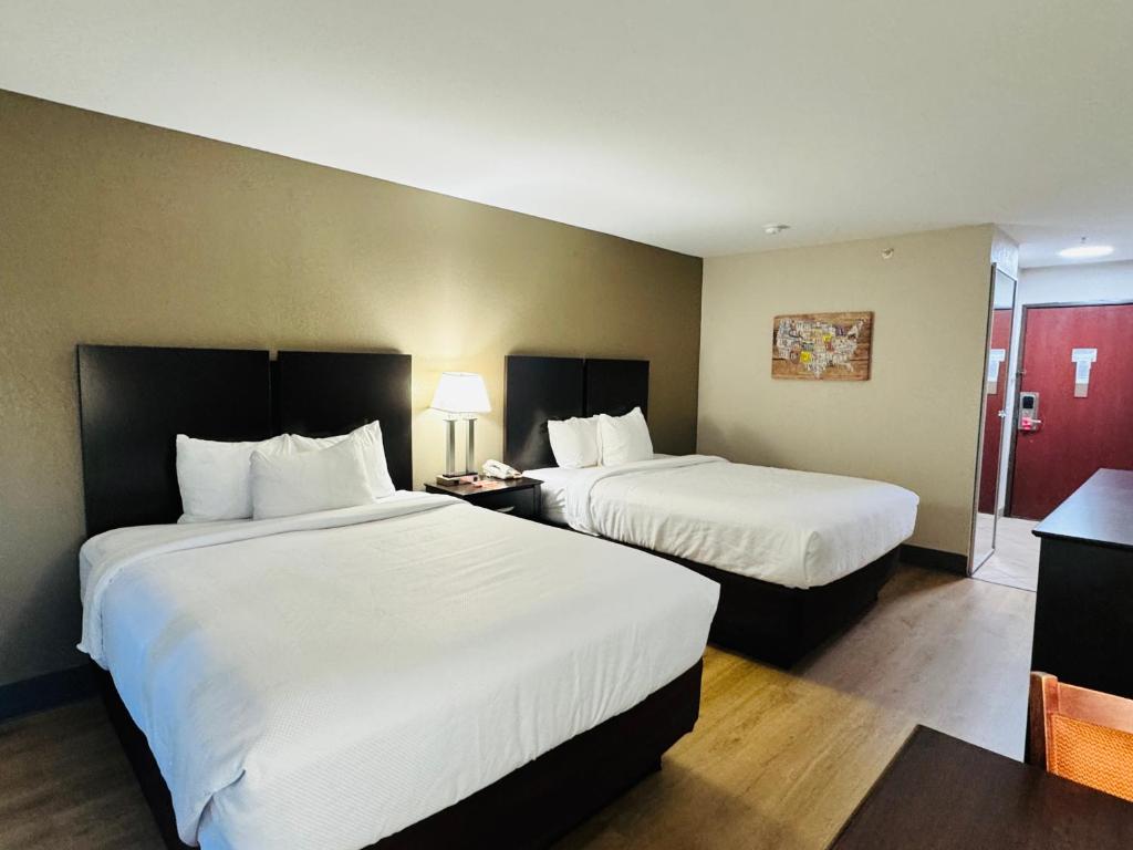 Una habitación de hotel con dos camas con sábanas blancas. en Econo Lodge Inn &amp; Suites Monroe, en Monroe