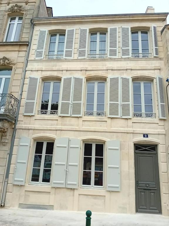 un bâtiment avec des fenêtres blanches à volets et une porte dans l'établissement Immeuble historique au pied du Château de Jonzac, à Jonzac