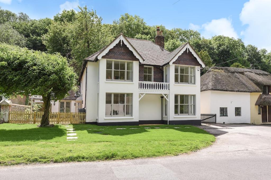 a large white house with a thatched roof at Luxury Large Five Bedroom Family House Sleeps 10 in Milton Abbas