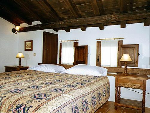 Casas del CastañarにあるCasa Rural La Cuevaのベッドルーム1室(ベッド1台、テーブルにランプ2つ付)