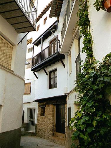 an alley with a white building with a balcony at CR La Cueva CR-CC-00114 in Casas del Castañar