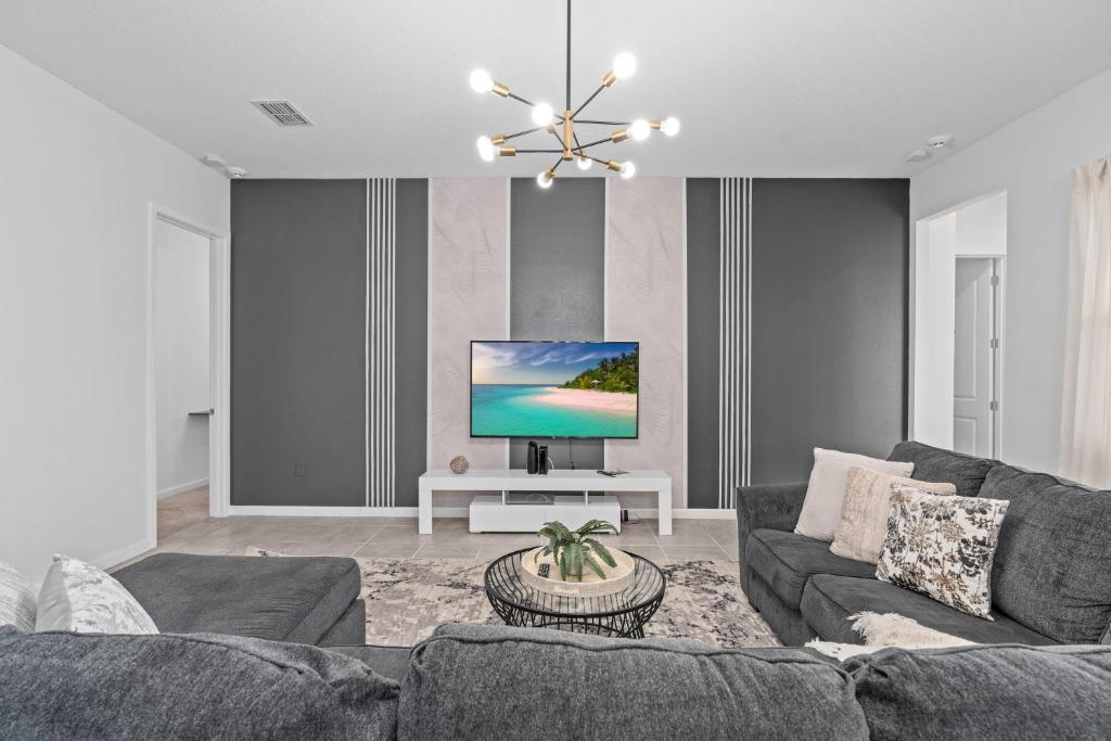 a living room with a couch and a tv at SUPER JUMBO - 12BD 12BAs SLEEPs 34 - w AMENITIEs in Kissimmee