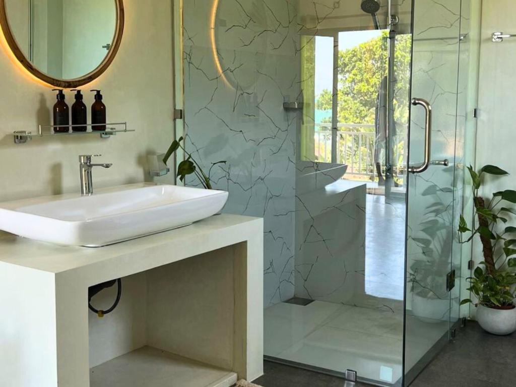 a bathroom with a sink and a glass shower at Calma - Surf, Yoga & Coffee on a Private Beach in Dickwella