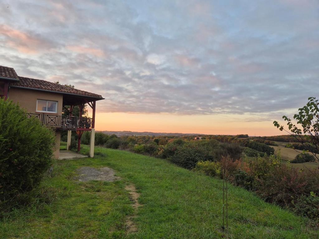une maison avec un balcon au-dessus d'un champ dans l'établissement Beautiful house with pool table in a green setting, à Lartigue