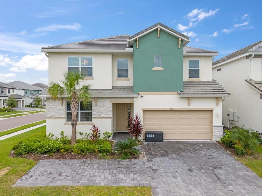 a house with a palm tree in front of it at SUPER LARGE - 12BD 12BAs - MANY ENSUITEs SLEEPs 30 in Kissimmee