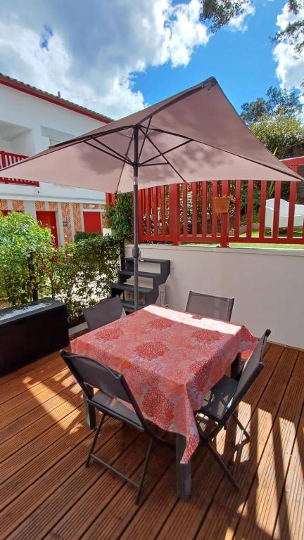 une table de patio avec un parasol sur une terrasse dans l'établissement Little Murmur - Détente absolue entre lac, golf et océan à Hossegor, à Soorts-Hossegor