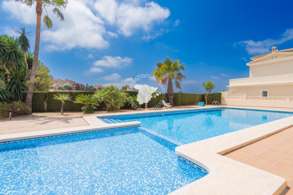 a swimming pool with palm trees and a building at CostaBlancaDreams Bungalow Gran Sol in Calpe in Calpe